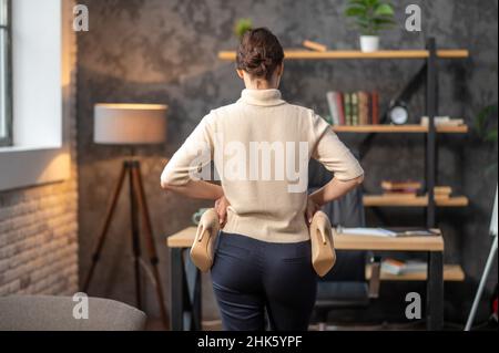 Femme tenant des chaussures à talons hauts dans ses mains Banque D'Images