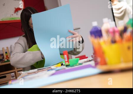 Darmstadt, Allemagne.02nd févr. 2022.Un éducateur portant un masque médical coupe une feuille de papier avec un enfant dans une garderie.Credit: Sebastian Gollnow/dpa/Alay Live News Banque D'Images