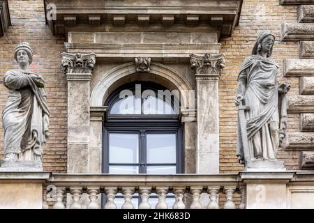 Fenêtre voûtée avec balcon, stuc, colonnes et statues sur le fond d'un mur de briques beige à Budapest.De la série Windows of the World. Banque D'Images