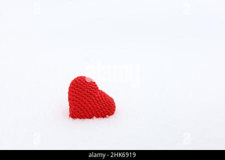 Coeur tricoté rouge dans la neige.Fond blanc pour la carte de Saint-Valentin, amour romantique Banque D'Images