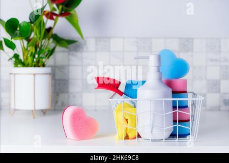 Concept d'entretien ménager.Savon à laver, éponges en forme de coeur, brosse et serviettes dans le panier sur la table avec plante verte.Mise au point sélective.Copier l'espace Banque D'Images