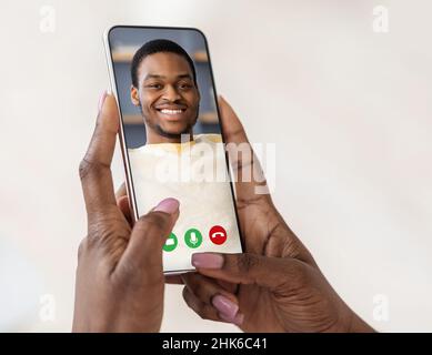 Femme noire tenant un téléphone portable dans la main vidéo d'appel petit ami Banque D'Images