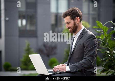 Un courtier en ligne réussi travaille avec un ordinateur portable, un homme d'affaires met en œuvre un plan de vente fonctionnant à distance Banque D'Images