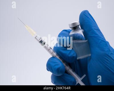 Main avec un gant médical tenant une bouteille de vaccin Banque D'Images
