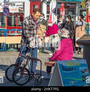 Homme aidant une femme handicapée en fauteuil roulant dans le parc.Homme assistant une femme âgée avec un marcheur de roue. Banque D'Images