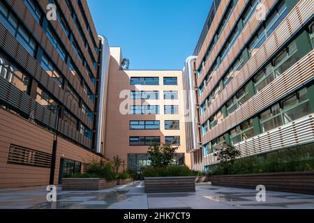 Tuyaux de ventilation en métal sur le mur extérieur d'un immeuble de bureau moderne, sur fond bleu ciel. Banque D'Images