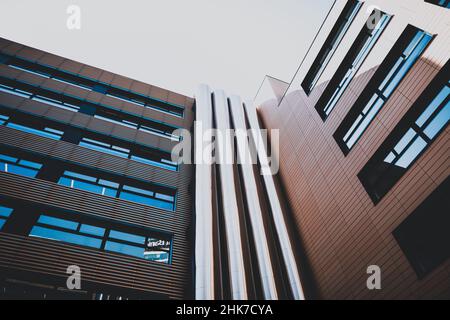 Tuyaux de ventilation en métal sur le mur extérieur d'un immeuble de bureau moderne, sur fond bleu ciel. Banque D'Images