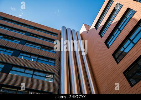 Tuyaux de ventilation en métal sur le mur extérieur d'un immeuble de bureau moderne, sur fond bleu ciel. Banque D'Images