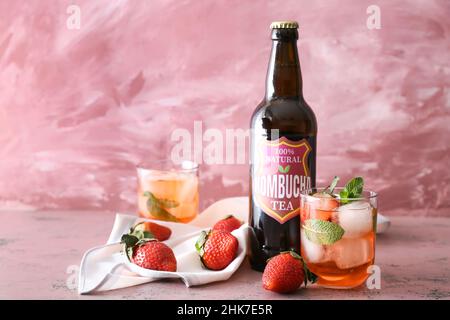 Bouteille et verre de kombucha frais de fraise glacé sur fond rose Banque D'Images