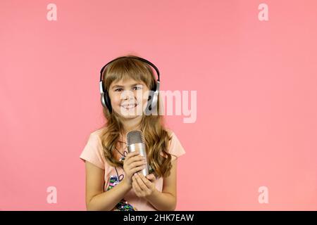 une petite fille gaie chante dans le microphone. Banque D'Images