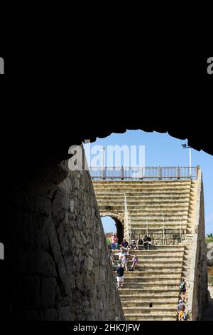 Les touristes s'assoient sur les anciens sièges de l'amphithéâtre Caesarea dans la ville romaine de Caesarea Maritima, dans le parc national de Caesarea en Israël. Banque D'Images