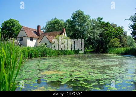 Willy Lott Cottage à Flatford, géré par le National Trust à Suffolk, en Angleterre. La rivière Stour, remplie de plantes, se trouve à l'extérieur du cottage rural. Banque D'Images