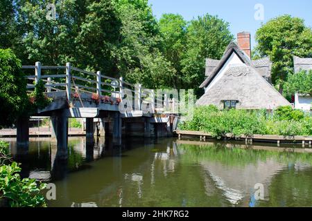 Bridge Cottage, un cottage de chaume du XVIe siècle situé à Flatford, Suffolk, Angleterre. Un pont en bois mène sur la rivière Stour par temps clair. Banque D'Images