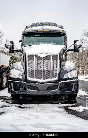 Tracteur semi-remorque classique noir avec calandre chromée et accessoires pour conducteur de camion sur le terrain de stationnement du chariot de manutention Banque D'Images