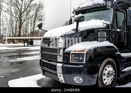 Tracteur semi-remorque classique noir avec calandre chromée et accessoires pour conducteur de camion sur le terrain de stationnement du chariot de manutention Banque D'Images