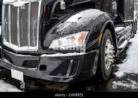 Tracteur semi-remorque classique noir avec calandre chromée et accessoires pour conducteur de camion sur le terrain de stationnement du chariot de manutention Banque D'Images