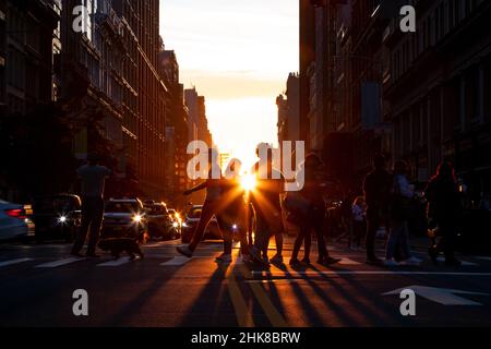 Silhouettes d'hommes et de femmes traversant une rue animée dans Midtown Manhattan, New York City, avec lumière du soleil brillant en arrière-plan Banque D'Images