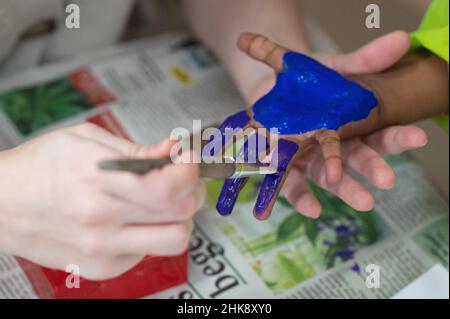 Darmstadt, Allemagne.02nd févr. 2022.Un enseignant peint la main d'un enfant avec de la peinture pour les doigts dans une garderie.L'Association des parents de Hesse réclame des règles de quarantaine uniformes dans les garderies de tout l'État.Credit: Sebastian Gollnow/dpa/Alay Live News Banque D'Images