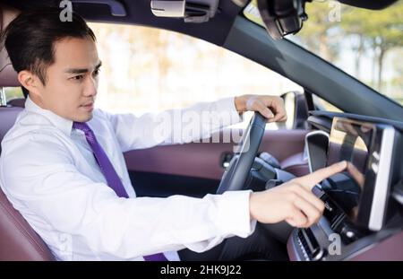 Beau jeune homme utilisant le système de navigation en conduisant la voiture Banque D'Images