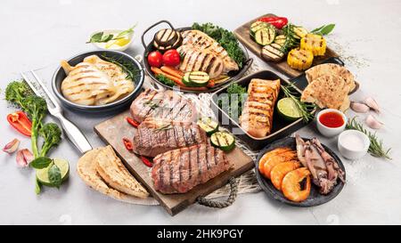 Assortiment de poissons, fruits de mer et viandes grillés sur fond clair.Concept de cuisine maison.Vue de dessus, plan d'appartement Banque D'Images