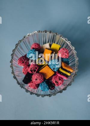 La réglisse britannique fait allusion aux bonbons dans un bol en cristal avec un fond bleu clair Banque D'Images