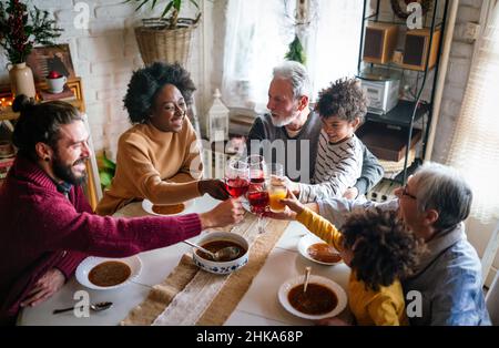 Bonne famille multiethnique multigénération s'amusant autour d'une table de cuisine. Banque D'Images