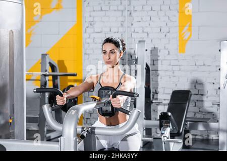 Moyen-Orient sportswoman s'entraîner avec la machine de crunch ab dans la salle de gym Banque D'Images