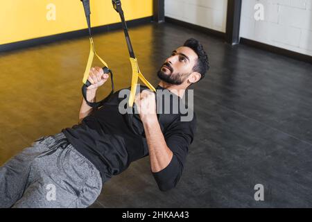 Entraînement de sportif musulman barbu avec sangles de suspension dans la salle de sport Banque D'Images