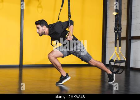 Vue latérale d'un sportif musulman qui s'entraîner avec des sangles de suspension dans la salle de sport Banque D'Images