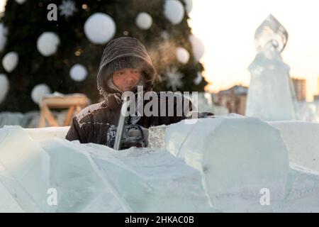 Le sculpteur coupe une figure hors de la glace par une tronçonneuse pour Noël Banque D'Images