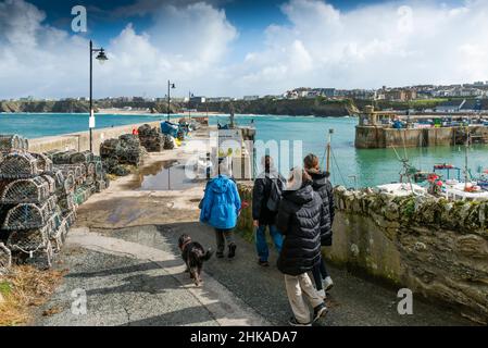 Une famille de vacanciers et leur chien marchant jusqu'au quai Nord dans le port pittoresque de Newquay, en Cornouailles. Banque D'Images