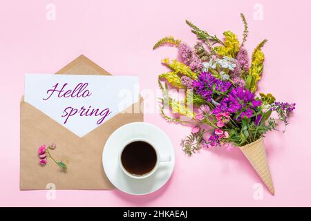 Bouquet de fleurs colorées en gaufre, tasse de café et enveloppe avec texte de carte Hello Spring sur fond rose carte de vœux Flat Lay vue du dessus C Banque D'Images