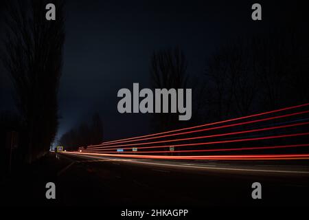 Feux rouges et blancs des voitures qui passent.Autoroute de nuit. Banque D'Images