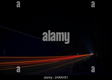 Feux rouges et blancs des voitures qui passent.Autoroute de nuit. Banque D'Images