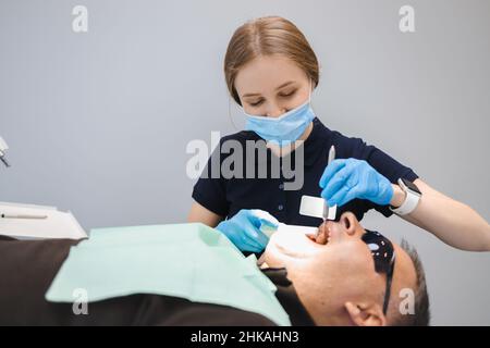 Dentiste femme remplissant les dents de l'homme Banque D'Images