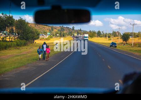 Vue du paysage par le conducteur passant par un village local sur une autoroute kenyane à travers la vallée du grand Rift à l'ouest de Nairobi, Kenya Banque D'Images