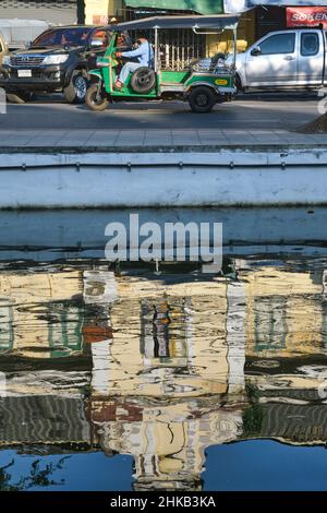 Réflexions d'un ancien bâtiment de style européen à Klong (canal) Lod le long de Atsadang Rd à Bangkok, Thaïlande, un tuk-tuk (taxi 3 roues) passant Banque D'Images