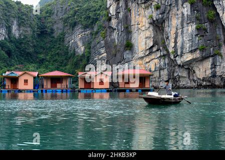 Homme sur son bateau avec le village flottant en arrière-plan Banque D'Images