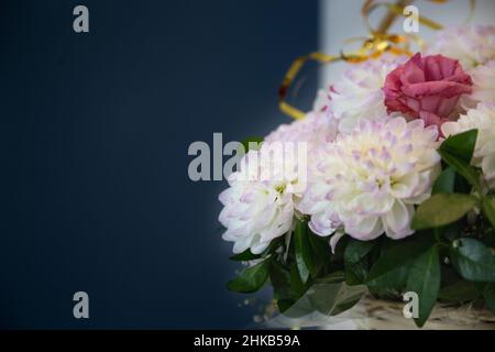 Bouquet de luxe dans vase artisanal, mur gris foncé. Fleuriste avec arrière-plan de l'espace de copie. Bouquet de dahlias blancs et roses rouges dans un panier fait à la main. Banque D'Images