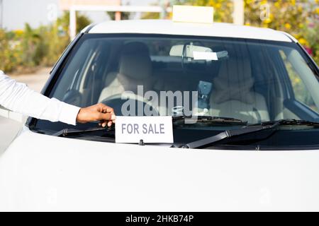 Gros plan du propriétaire plaçant la voiture à la vente panneau d'affichage devant la voiture - concept de perte d'affaires, problèmes personnels, chips financières, faillite et Banque D'Images