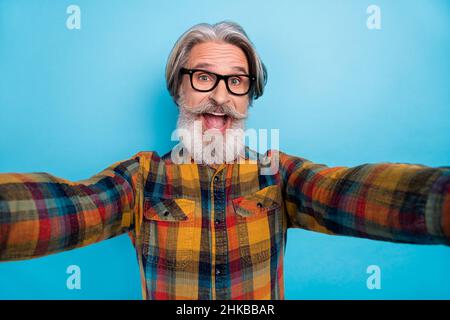 Photo de l'homme impressionné funky retraité porter une chemise à carreaux lunettes tking selfie bouche ouverte isolé couleur bleue fond Banque D'Images