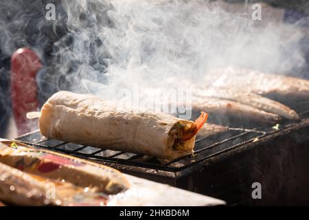 Faire Balik Ekmek sur feu de bois à Istanbul, Turquie, une cuisine traditionnelle turque de rue faite de maquereau grillé enveloppé de légumes dans du pain Banque D'Images