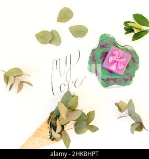 Plaque d'art en résine avec cadeau, carte « My Love » en papier et eucalyptus sur fond blanc.Vue de dessus Banque D'Images