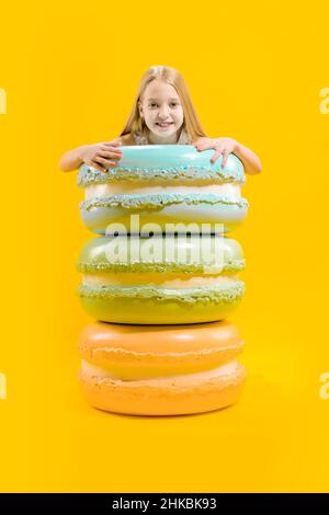 Dessert rond.Douceur de Noël.Une jolie fille se tient derrière des macarons, les tenant avec ses mains.Cadeau sucré. Banque D'Images