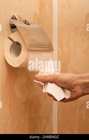 la main de l'homme déchire un morceau de papier toilette dans les toilettes.Photo de haute qualité Banque D'Images