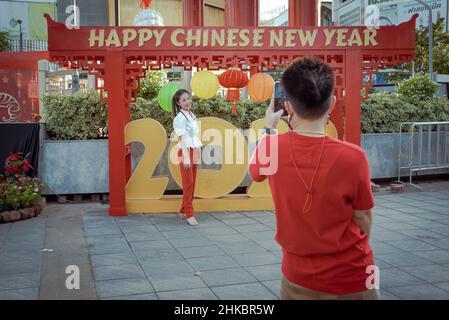 Un homme prend une photo d'une femme qui pose par une exposition chinoise du nouvel an.le nouvel an lunaire à Bangkok cette année est une affaire plus solennelle que les années précédentes.Le gouvernement avait techniquement annulé de grandes célébrations, mais dans le quartier chinois, une troupe de danseurs de lion ralentissait la circulation sur la route de Yaowrat.Dans une rue latérale de Wat Lokanukroh, la seule excitation pour la journée a été l'apparition d'un petit incendie causé par l'effondrement de grandes bougies rouges allumées l'une sur l'autre; les gardiens se sont précipités pour un extincteur.De nombreux thaïlandais d'origine chinoise continuèrent à accomplir des rites et des prières au sanctuaire de l'indicent Banque D'Images