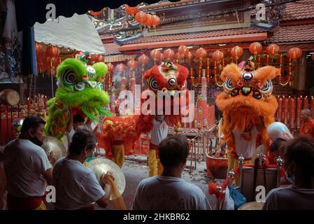 Trois danseurs de lion et des membres de leur troupe se produisent à l'extérieur d'un temple.le nouvel an lunaire à Bangkok cette année est une affaire plus solennelle que les années précédentes.Le gouvernement avait techniquement annulé de grandes célébrations, mais dans le quartier chinois, une troupe de danseurs de lion ralentissait la circulation sur la route de Yaowrat.Dans une rue latérale de Wat Lokanukroh, la seule excitation pour la journée a été l'apparition d'un petit incendie causé par l'effondrement de grandes bougies rouges allumées l'une sur l'autre; les gardiens se sont précipités pour un extincteur.De nombreux thaïlandais d'origine chinoise ont continué d'effectuer des rites et des prières au sanctuaire de l'undi Banque D'Images