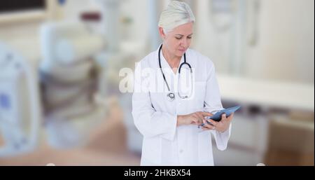 Femme de race blanche mature médecin utilisant une table numérique tout en se tenant dans le théâtre d'opération Banque D'Images