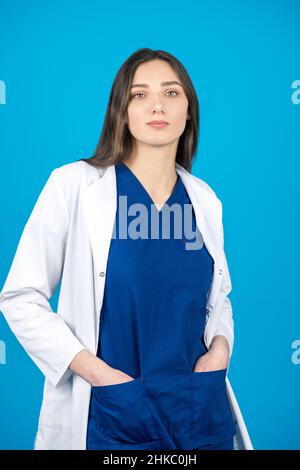 Concept de soins de santé et de médecine.Portrait de brunette cheveux longs belle femme médecin tenant ses mains dans les poches et portant blanc et bleu medici Banque D'Images