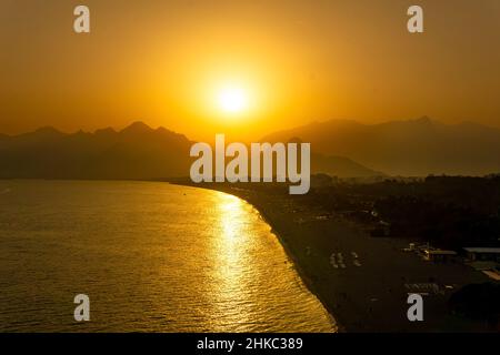 Antalya, Turquie - 15 novembre 2021 : coucher de soleil sur la plage de Konyaalti depuis les rochers à proximité.Les montagnes de Beydaglari dans le brouillard sont visibles en arrière-plan. Banque D'Images